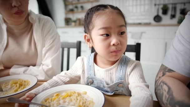 アジアの子供は親とコーンフレークを食べる 若い家族が家で朝食を食べている 手持ちのカメラ — ストック動画