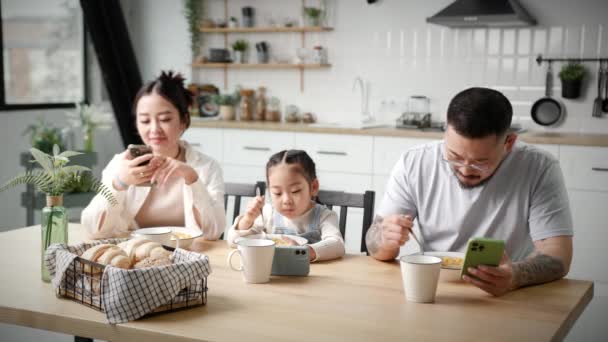 家族で食べるとお互いを無視してスマートフォンを見て アジアの家族は 朝食時に携帯電話を使用してお互いをパブ — ストック動画