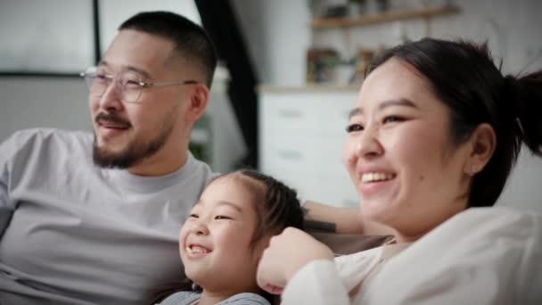 快乐的家庭笑着看电视吃爆米花近身 家里只有一个孩子 坐在沙发上玩得很开心的韩国家庭 — 图库视频影像