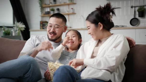 家人看电视吃爆米花 家里只有一个孩子 坐在沙发上玩得很开心的韩国家庭 妈妈和爸爸和女儿笑得很开心4K — 图库视频影像