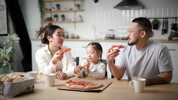 家人在家吃比萨 有一个孩子的亚洲家庭一边吃披萨一边笑着看着相机 爸爸和女儿一起享受披萨时间 — 图库视频影像