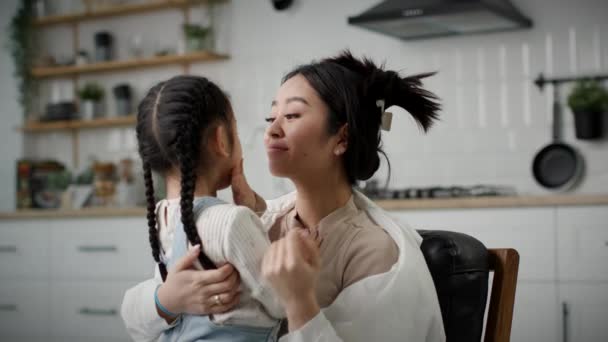爱妈妈拥抱她的女儿 快乐的亚洲妈妈和女孩拥抱和亲吻坐在家里 — 图库视频影像