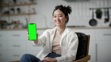 Kamerada Yeşil Ekran Cep Telefonu Tutan Kadın. Gülümseyen Koreli kadın kameraya hücre krom ekranı gösteriyor. 4K