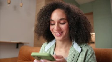 Cep Telefonu ile Kadın Mesajlaşması. Karışık ırktan bir kadın akıllı telefon kullanarak internette sohbet ediyor. Hücrede tutulan gülümseyen genç bir yetişkin. 4K