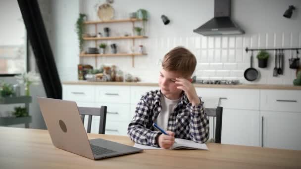在家里用笔记本电脑上网学习的孩子 男孩子用笔记本电脑和笔记本做作业 — 图库视频影像