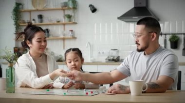 Aile Ölülerle Masa Oyunu oynar. Küçük kız, anne ve babasıyla evde oturmuş oyun oynuyor. 4K