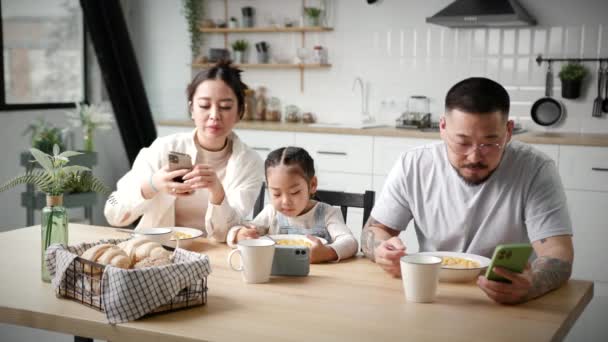 Rodzinne Jedzenie Pomocą Gadżetów Azjatycka Rodzina Płatki Kukurydziane Ogląda Telefony — Wideo stockowe