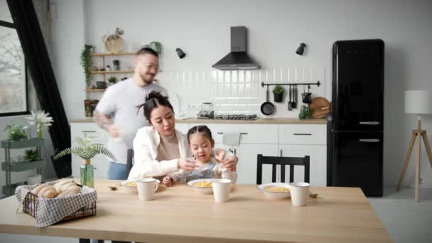 アジア系の家庭で朝食を食べる お母さんとお父さんとコーンフレークを食べる女の子 素敵な家族が一緒に幸せ — ストック動画