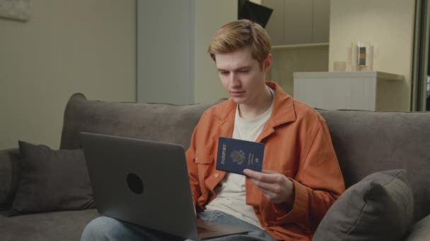 男は手に米国のパスポートを保持ノートパソコンを入力します オンラインで働いている白人は自宅のオフィスに座っている — ストック動画