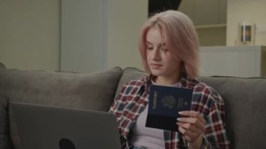 Dizüstü bilgisayarda yazan kadın ABD pasaportunu elinde tutuyor. Vergi formunu dolduran beyaz bir kadın ev ofisinde oturuyor. 4K