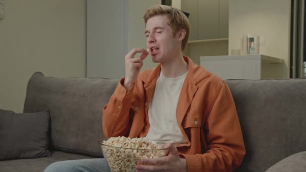 Mannen Skrattande Äta Popcorn Sitter Soffan Hemma Ung Vuxen Man — Stockvideo