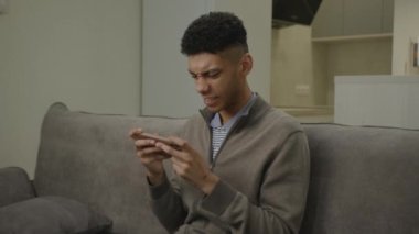 Video Oyunu Kazanan Siyah Adam Cep Telefonu Kullanıyor. Mobil oyun uygulaması oynayan mutlu Afrikalı Amerikalı adam akıllı telefonu elinde tutuyor. 4K