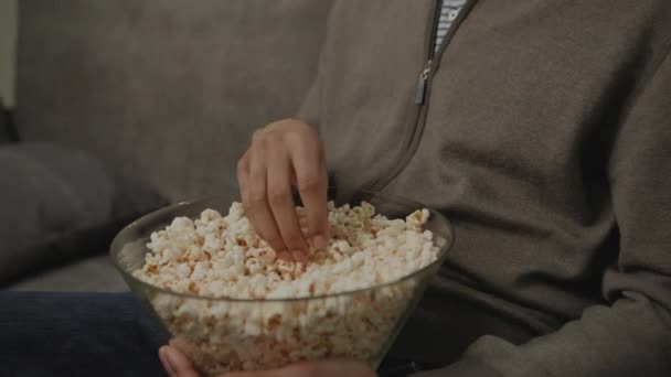 Mężczyzna Dwudziestce Jedzący Popcorn Siedzący Kanapie Domu Afroamerykanin Ogląda Telewizję — Wideo stockowe
