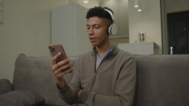 Siyah Adam Şarkı Söylüyor, Zeka Telefonu Tutuyor. 20 'li yaşlarda erkek, evdeki koltukta oturan kulaklıkla müzik dinlemekten hoşlanır. 4K