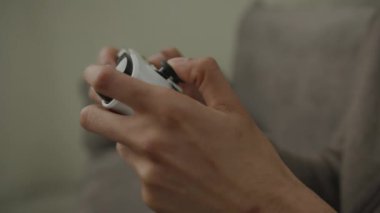 Video oyunu için Siyah Eller Joystick kullanıyor. 20 'li yaşlarda erkek video oyunu oynuyor. Evdeki kanepede oturuyor. 4K