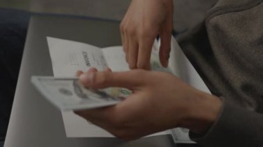 Siyah erkek eller Amerikan dolarlarını sayıyor. Tanınmayan Afro-Amerikan bir adam evde oturarak faturaları ödüyor. 4K