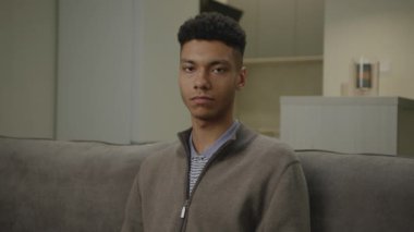 Koltukta oturan tatmin olmuş siyah adam. Afro-Amerikalı adam kameraya bakıp gülümsüyor. 4K