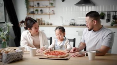 Asyalı Aile Pizza Yiyiyor. Anne, baba ve kızı pizza servisinin keyfini çıkarmaya hazır. Mutlu aile zamanları. 4K