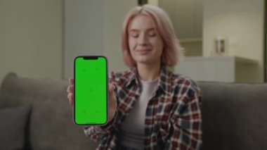 Milenyum kadını Kamera 'da Yeşil Ekran Cep Telefonu Gösteriyor. Elinde krom anahtar cep telefonu tutan gülümseyen bir kadın. 4K