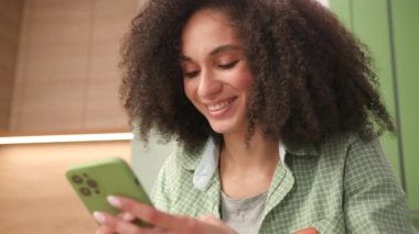 Karışık Irk Kadını Akıllı Telefon Kullanıyor. Cep telefonuyla internette gezen mutlu kadın. Gülümseyen genç yetişkin hücreyi kullanarak mesaj atıyor. 4K