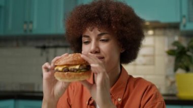 Ellerinde Burger tutan siyah kadın. Aç Afrika kökenli Amerikalı kadın hamburger yemeye hazır. 4K