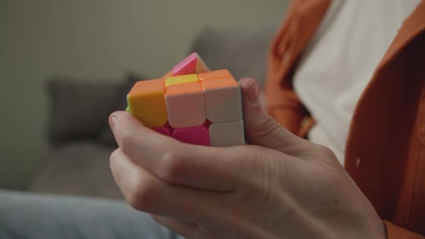 人类解决方块拼图 聪明的年轻人坐在家里的沙发上玩立方体拼图 — 图库视频影像