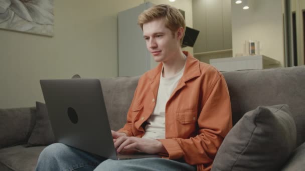 White Man Εργάζονται Απευθείας Σύνδεση Χρησιμοποιώντας Laptop Στον Καναπέ Millennial — Αρχείο Βίντεο