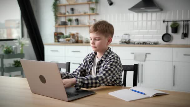 男生在家里用笔记本电脑坐着学习 男孩在电脑上打字 做作业 — 图库视频影像