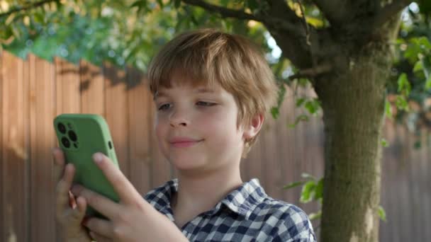孩子用手机站在户外 男孩在街上拿着智能手机上网浏览 — 图库视频影像