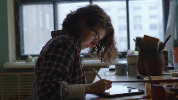 タブレットコンピュータを使用したデザイナー 30代の女性が机の上の机の上に座って絵を描いていました — ストック動画