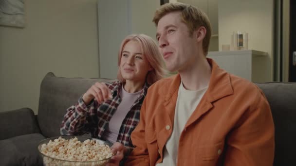 Para Dwudziestce Ogląda Telewizję Popcorn Rozmawia Kanapie Domu — Wideo stockowe
