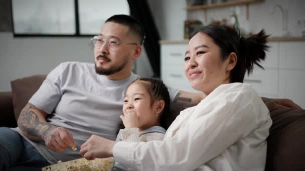 Azjatycka Rodzina Ogląda Telewizję Jedzącą Popcorn Kanapie Szczęśliwi Rodzice Śmieją — Wideo stockowe