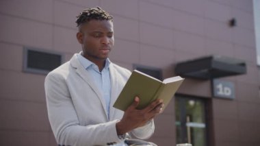 Siyah Adam Dışarıda Oturan Kitap Okuyor. İş adamı dışarıda kitap okuyarak rahatlıyor. 4K