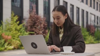 İnternette çalışan Asyalı iş kadını. Kafede dizüstü bilgisayar kullanan genç, yetişkin bir girişimci. 4K