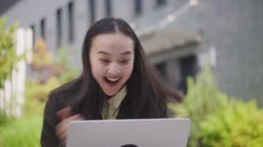 Asyalı Kadın dizüstü bilgisayarda iyi haberleri okurken çok heyecanlı. Mutlu kadın harika bir iş teklifi alıyor. İnternette kazanan kadın. Yakın çekim. 4K