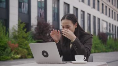Asyalı iş kadını laptopta kötü haberleri okuyor. Dışarıda dizüstü bilgisayar kullanan üzgün bir kadın. 4K