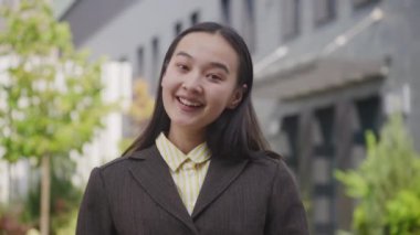 Dışarıdaki kamerada konuşan Asyalı iş kadını. Neşeli bayan kameraya bakıyor. 4K
