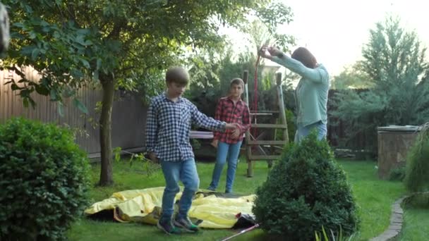 母と息子が一緒にテントを建てている 母親が裏庭にテントを設置するのを手伝う子供たち 4Kについて — ストック動画