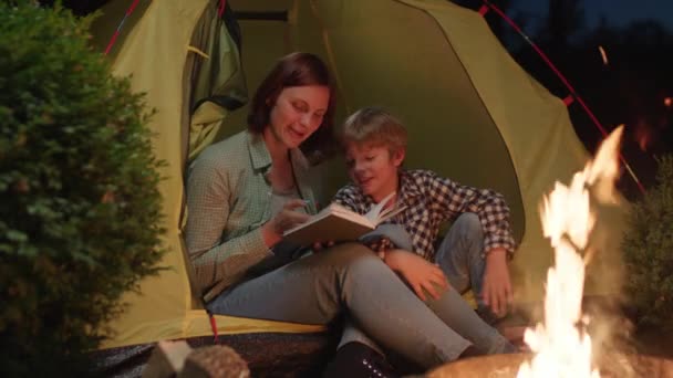Mutter Liest Ihrem Sohn Lagerfeuer Ein Buch Vor Familiencamping Abend — Stockvideo