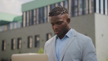 Siyah adamın dışarıda dizüstü bilgisayar kullanan bir fikri var. Çevrimiçi çalışan Afrikalı Amerikalı erkek. Kapatın. 4K