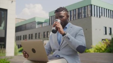 Siyah İş Adamı, Bilgisayardan İyi Haberler Aldı. Mutlu Afrikalı Amerikalı girişimci dışarıda dizüstü bilgisayarla çıktı. 4K