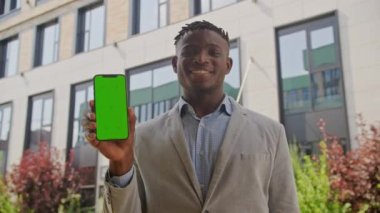 Siyah Adam Yeşil Ekran Cep Telefonu Tutuyor ve Kameraya Bakıyor. Afrikalı Anerikli İşadamı dışarıda krom anahtar telefon ekranı gösteriyor. 4K