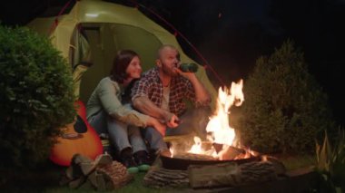 Geceleri kamp ateşinin yanında çadırda oturan çift. Gitarlı aile kampı. Karı koca şöminenin başında sosis pişiriyor. 4K