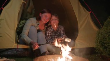 Anne ve Oğlu kamp ateşinde lokum kızartıyorlar. Aile kamp yemeklerini sever. 4K