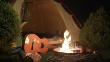 Gitar, Karanlıkta Çadır ile Kamp Ateşi 'nin yanında. Geceleri insanların olmadığı bir kamp alanı. 4K