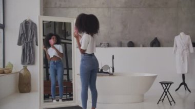 Banyoda saçını tarayan 20 'li yaşlarda bir kadın. Evde dans edip şarkı söyleyen pozitif siyah kadın. 4K