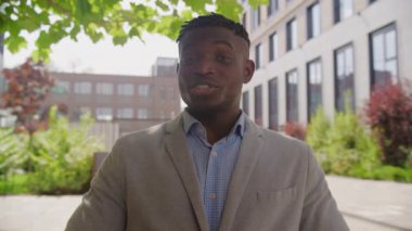 Siyah adam dışarıda kamerada konuşuyor. Afro-Amerikan işadamı kendinden emin bir şekilde dışarıda oturan kameraya bakıyor. 4K