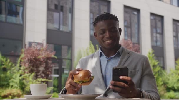 Czarny Człowiek Hamburgera Przegląda Komórkę Biznesmen Jedzący Piszący Smsy Przez — Wideo stockowe