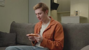 Beyaz adam akıllı telefonda video oyunu kaybediyor. Üzgün adam koltukta otururken cep telefonu oyununu kaybetti. 4K