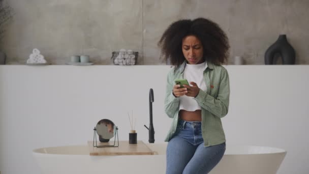 Чорна Жінка Читає Погані Новини Мобільному Телефоні Сидячи Вдома Жінка — стокове відео